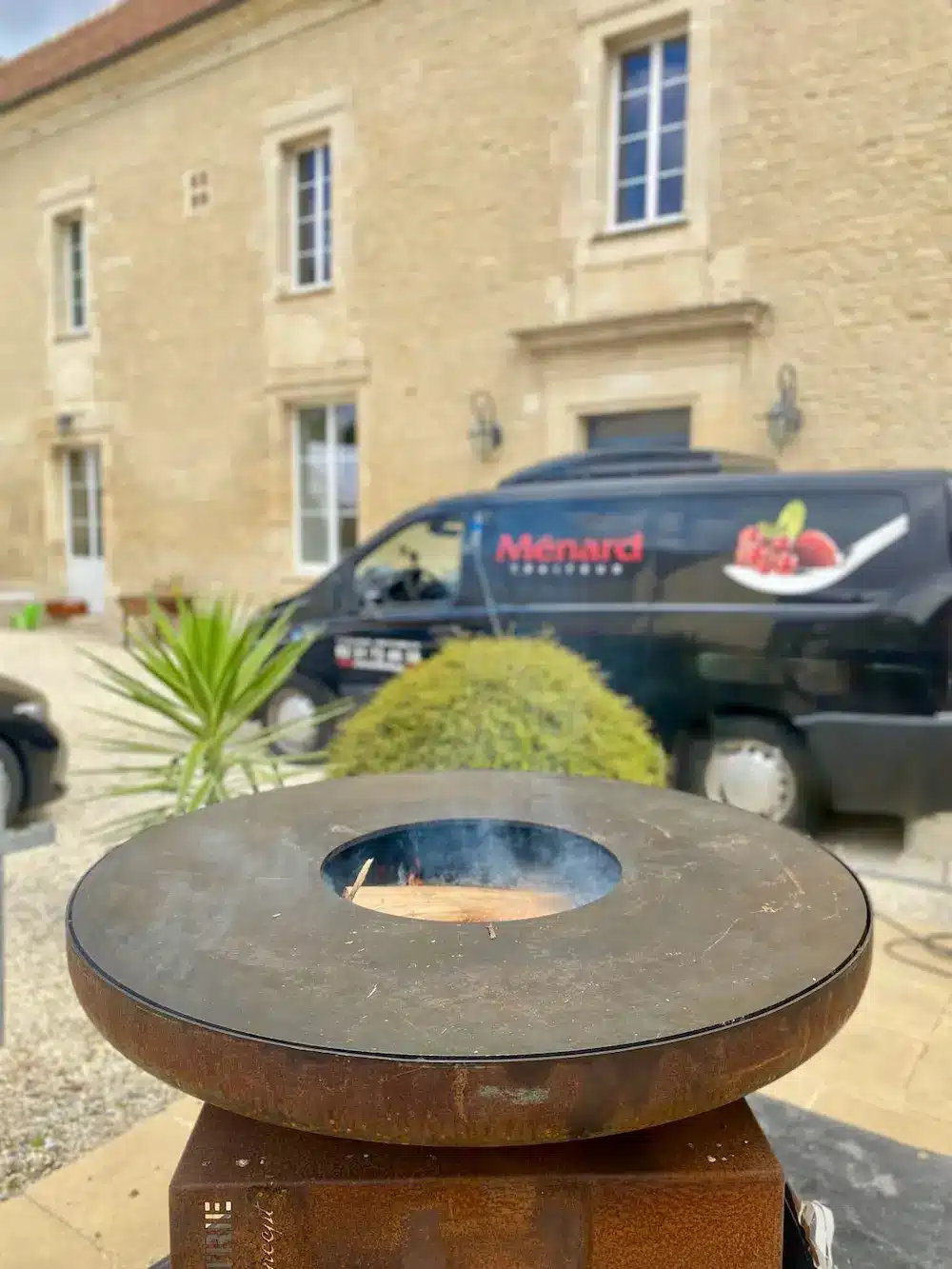 Photo gros plan sur un braséro avec en arrière plan un véhicule de Menard Traiteur Caen. Evénementiel pour entreprise